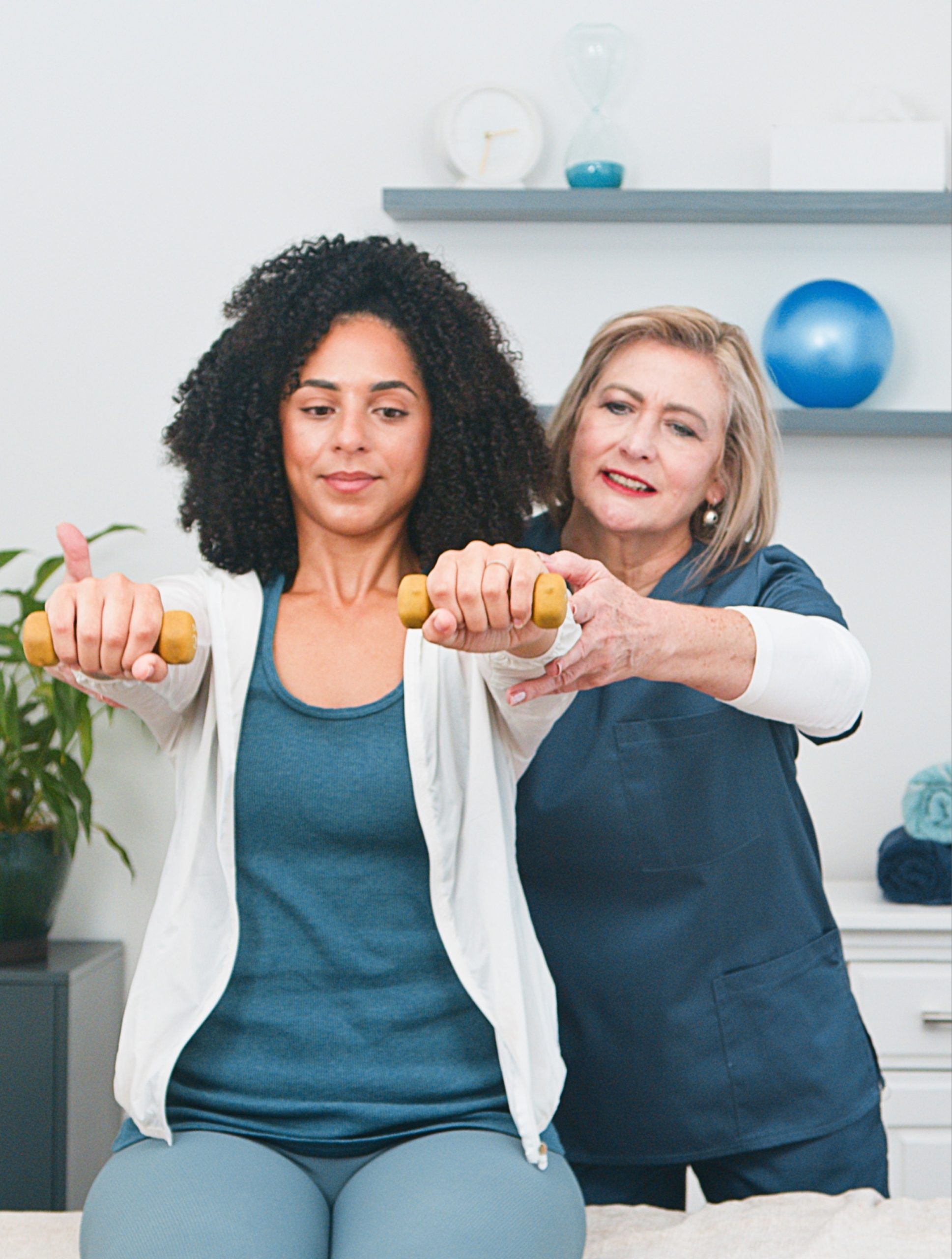 A physiotherapist guiding a patient through a rehab exercise with dumbbells